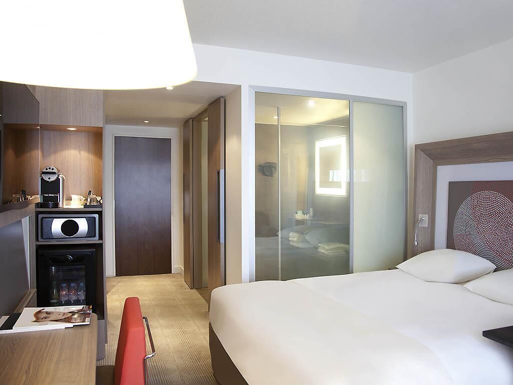 Una habitación de hotel con cama, escritorio con cafetera, armario y closet con puerta corrediza.