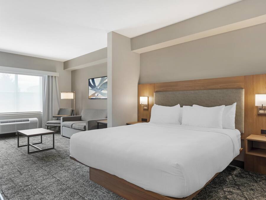 Una habitación de hotel con una cama grande, un escritorio, una silla y una ventana.