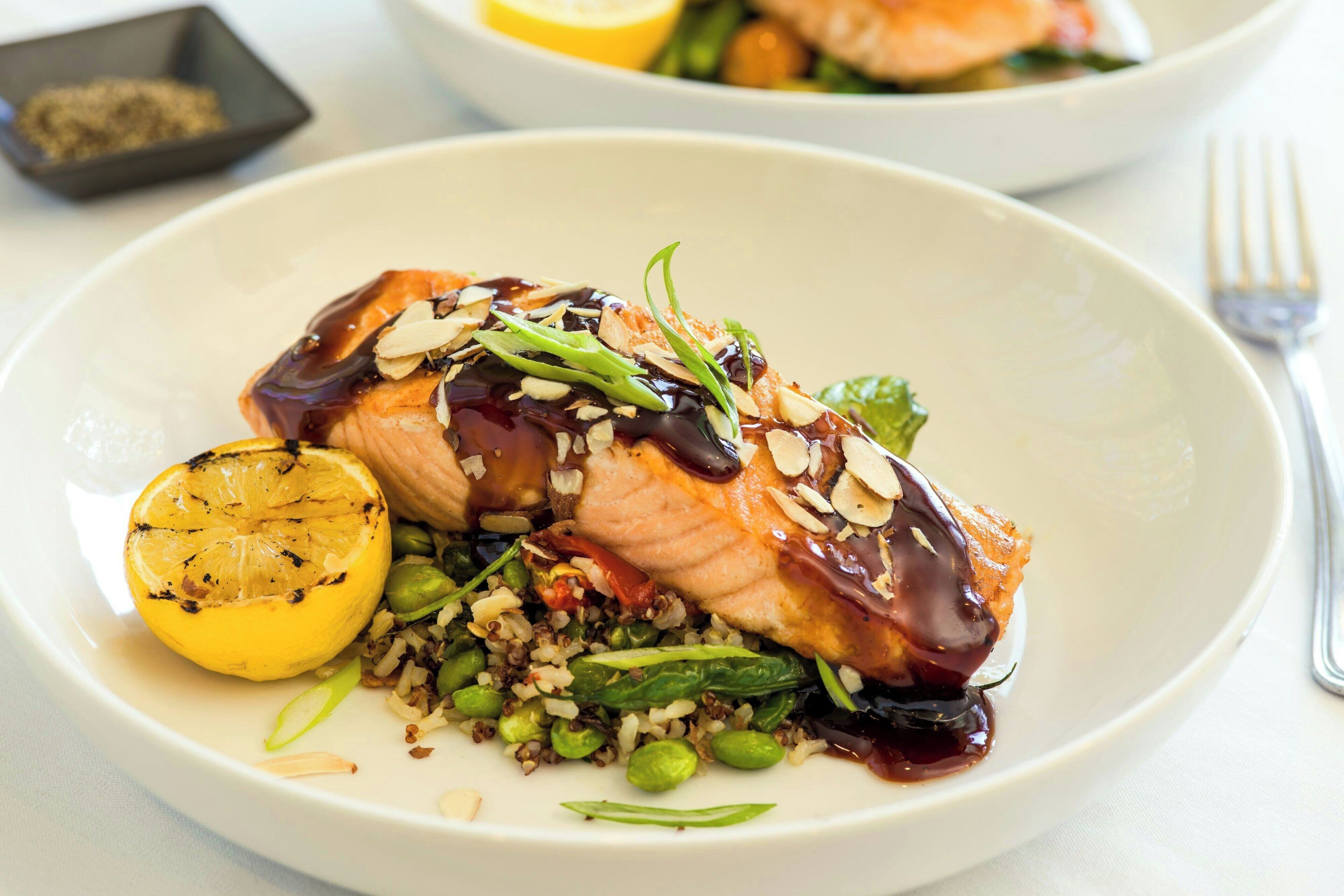 Une assiette de nourriture composée de saumon, de quinoa et de citron.