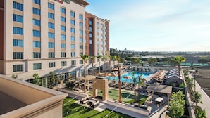 A hotel with a pool area, outdoor seating, and a view of the surrounding landscape.