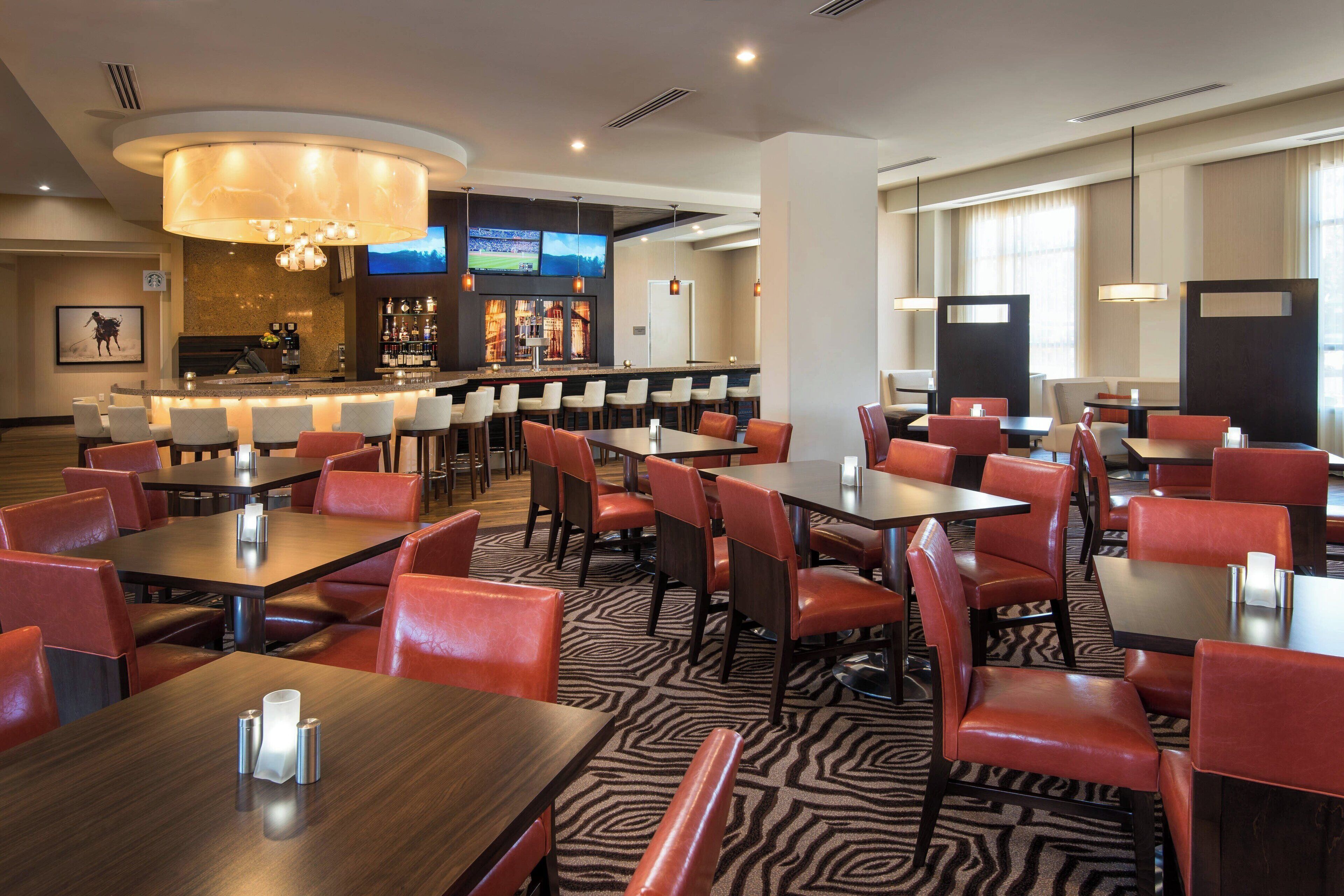 A hotel restaurant with a bar area, multiple tables and chairs, and a zebra-patterned floor.