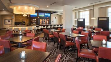 A hotel restaurant with a bar area, multiple tables and chairs, and a zebra-patterned floor.