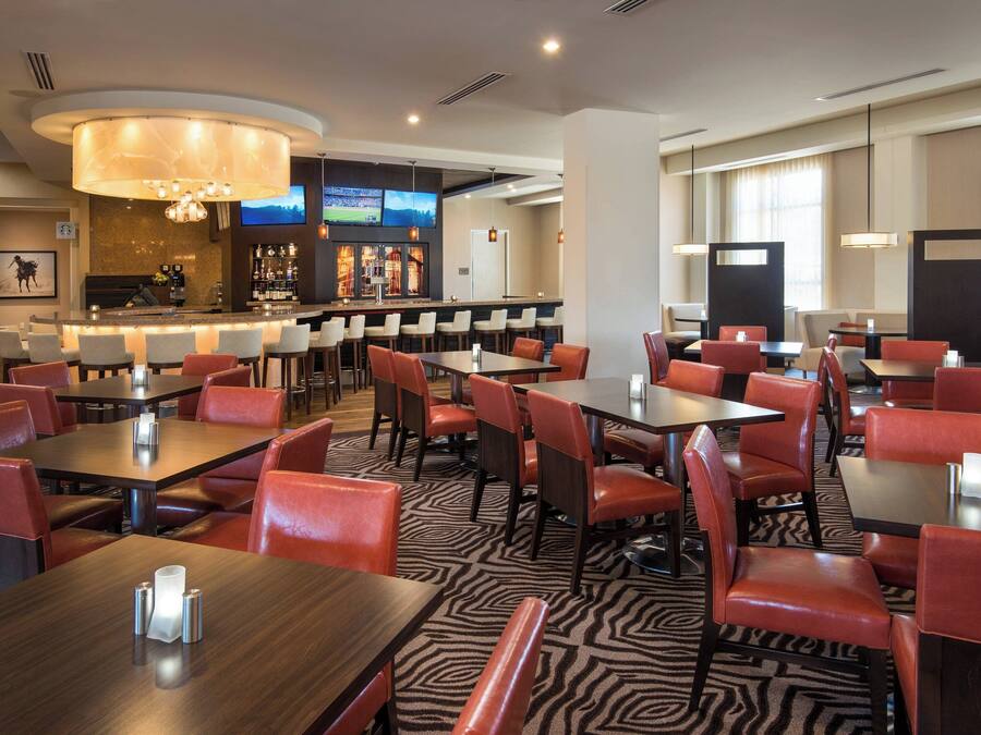 A hotel restaurant with a bar area, multiple tables and chairs, and a zebra-patterned floor.