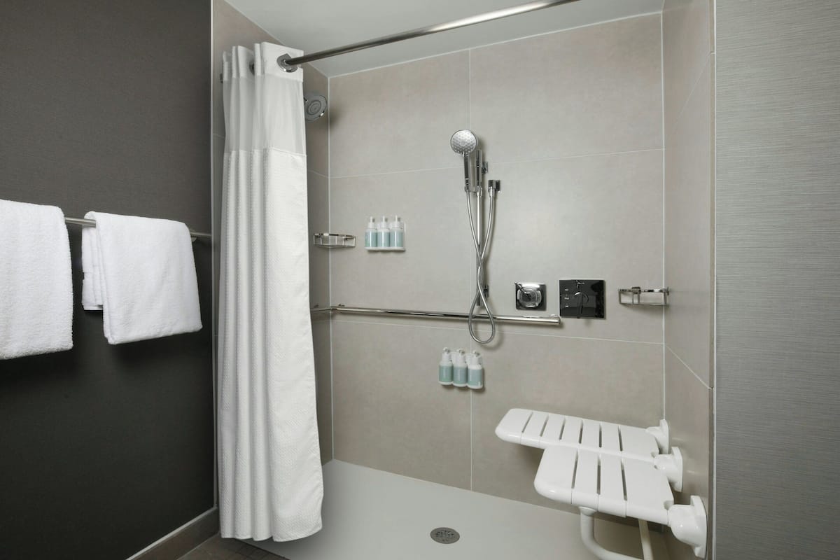 A modern shower area with a handheld showerhead, a glass shower enclosure, and a white towel rack.
