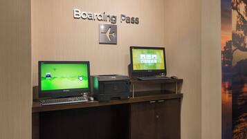 A desk with a computer, a printer, and a sign that reads "Boarding Pass".