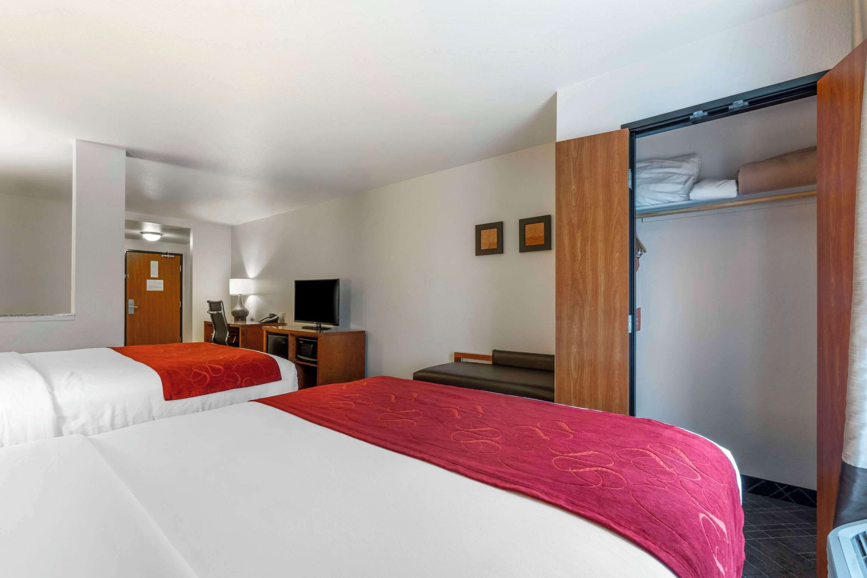 Une chambre d’hôtel avec deux lits, un bureau, une télévision et une armoire.