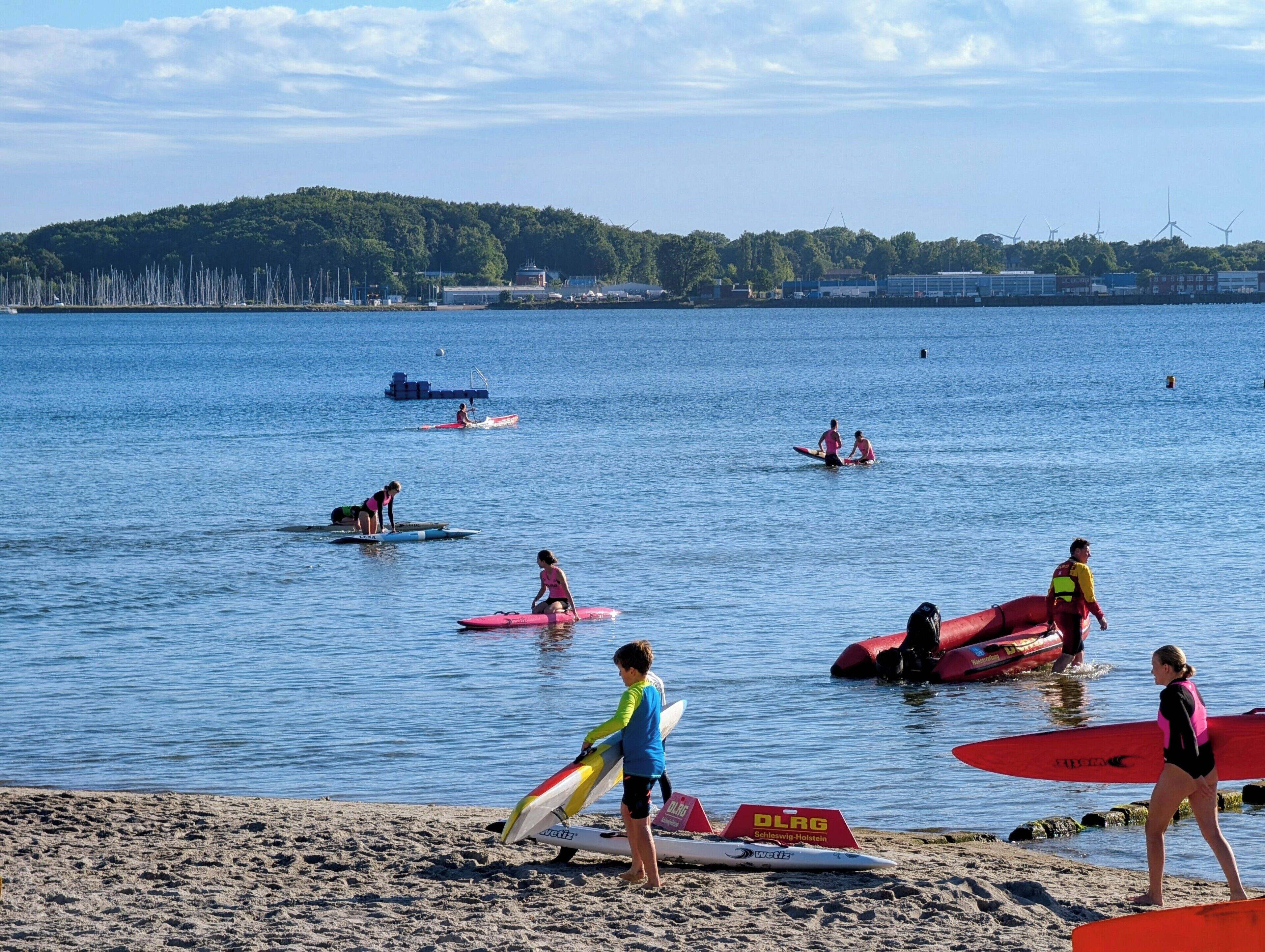 A beach with people on surfboards and a lifeguard in the water.