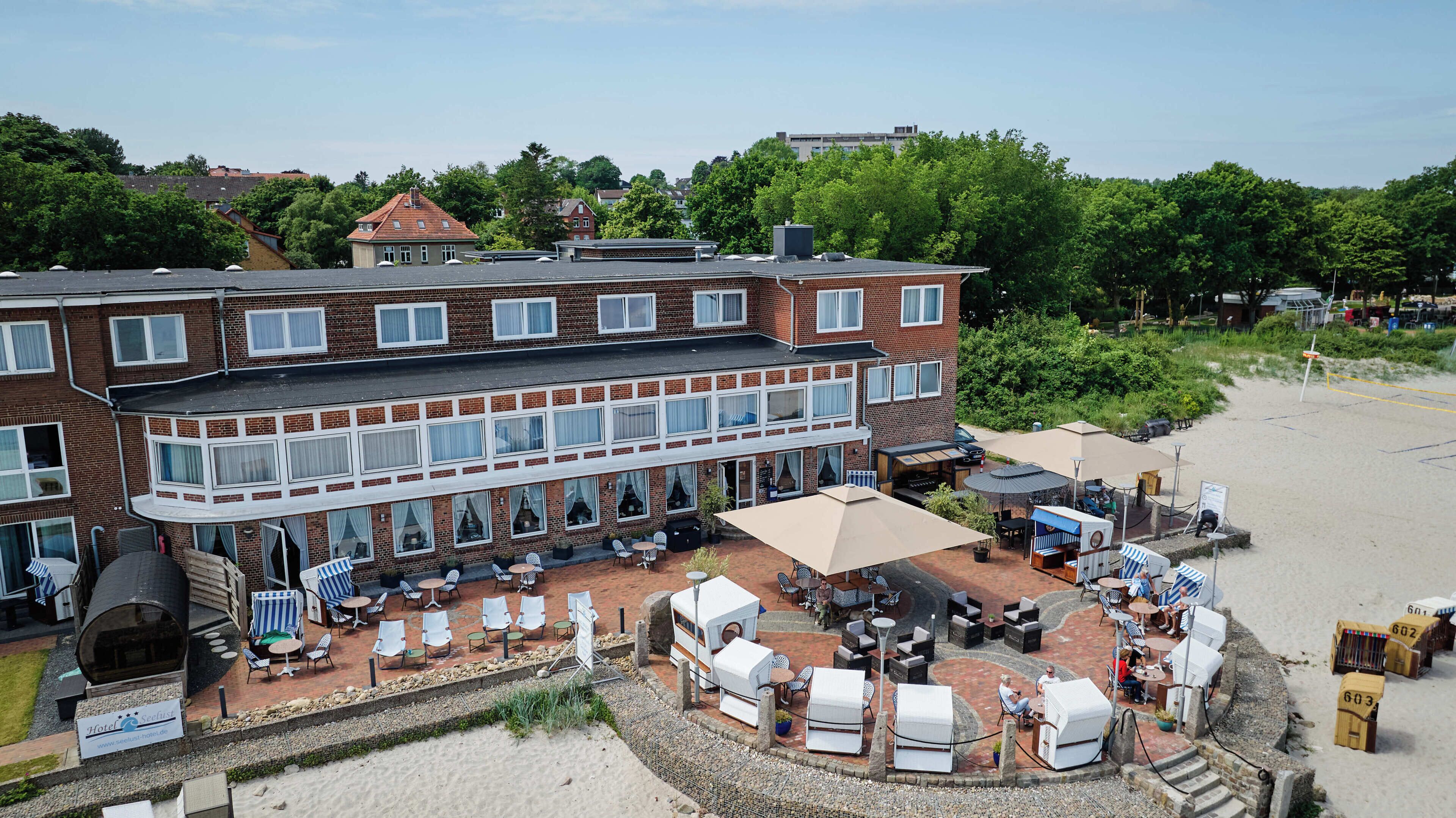 A hotel with a brick facade, outdoor seating, and a beach view.