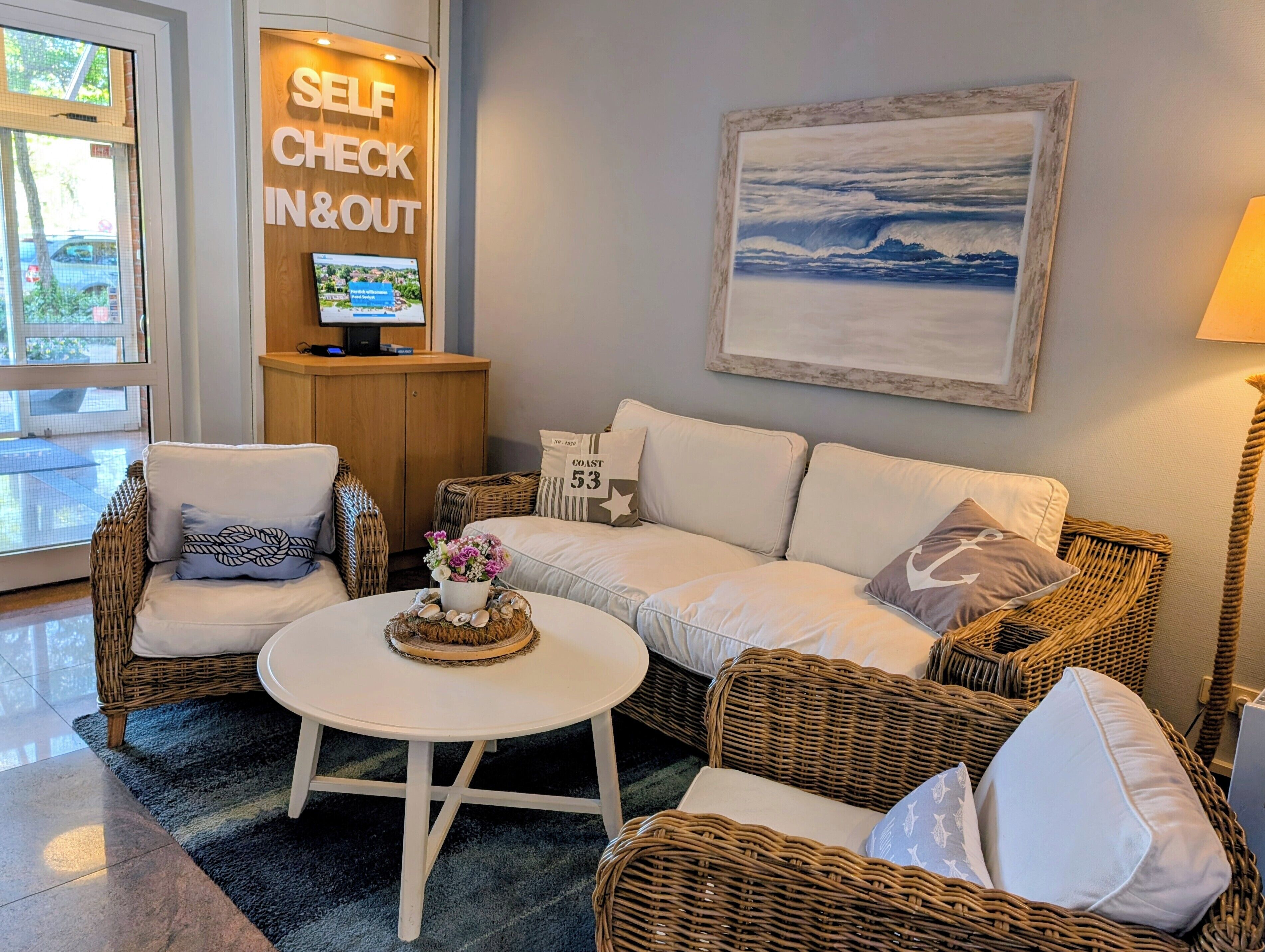 A cozy room with wicker furniture, a white sofa, and a round table with a floral centerpiece.
