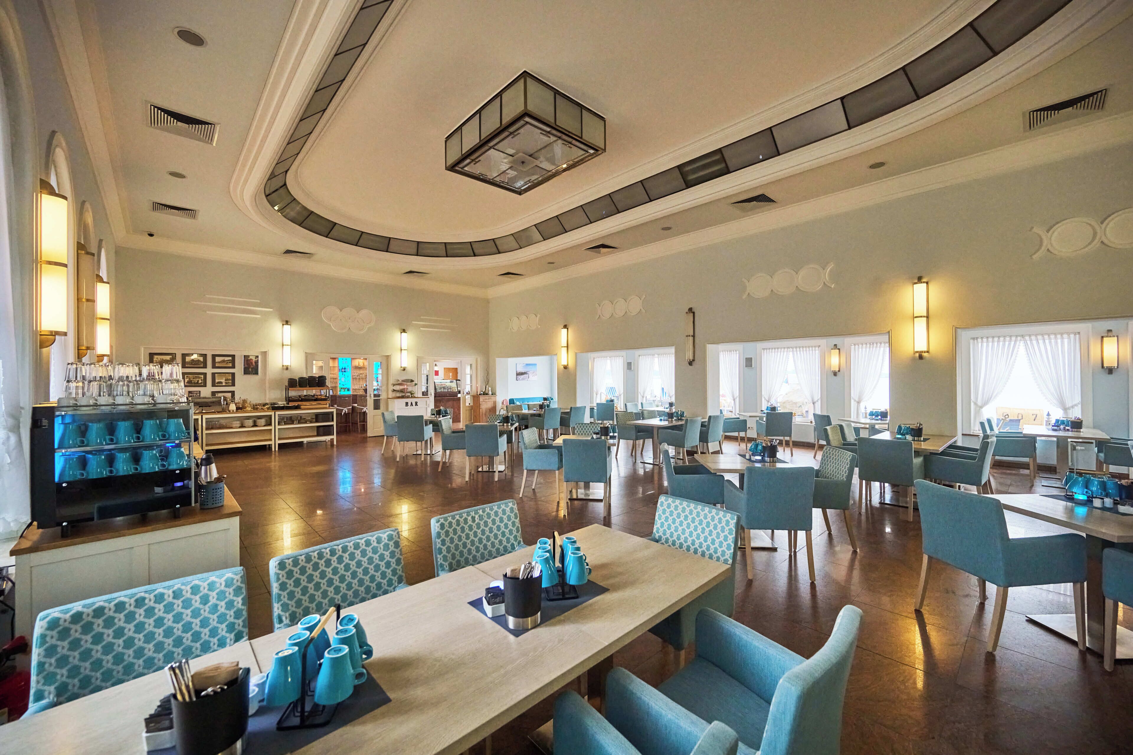 A spacious dining area with multiple tables and chairs, a buffet station, and a bar area.