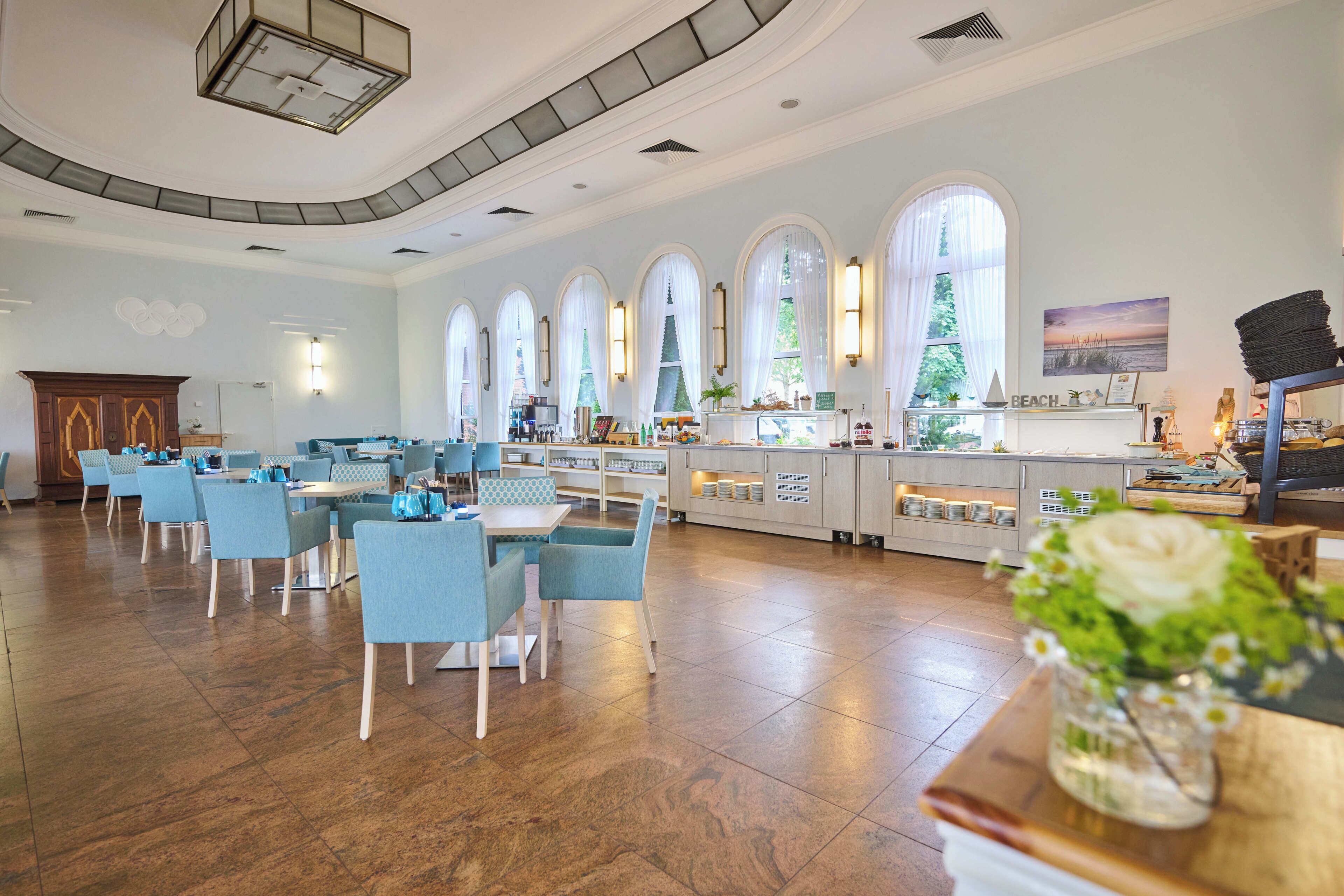 A spacious hotel lobby with multiple seating areas, a reception desk, and large windows.