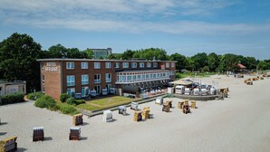 Un hôtel à étages, doté d’une terrasse et d’un espace sablonneux avec des chaises de plage.