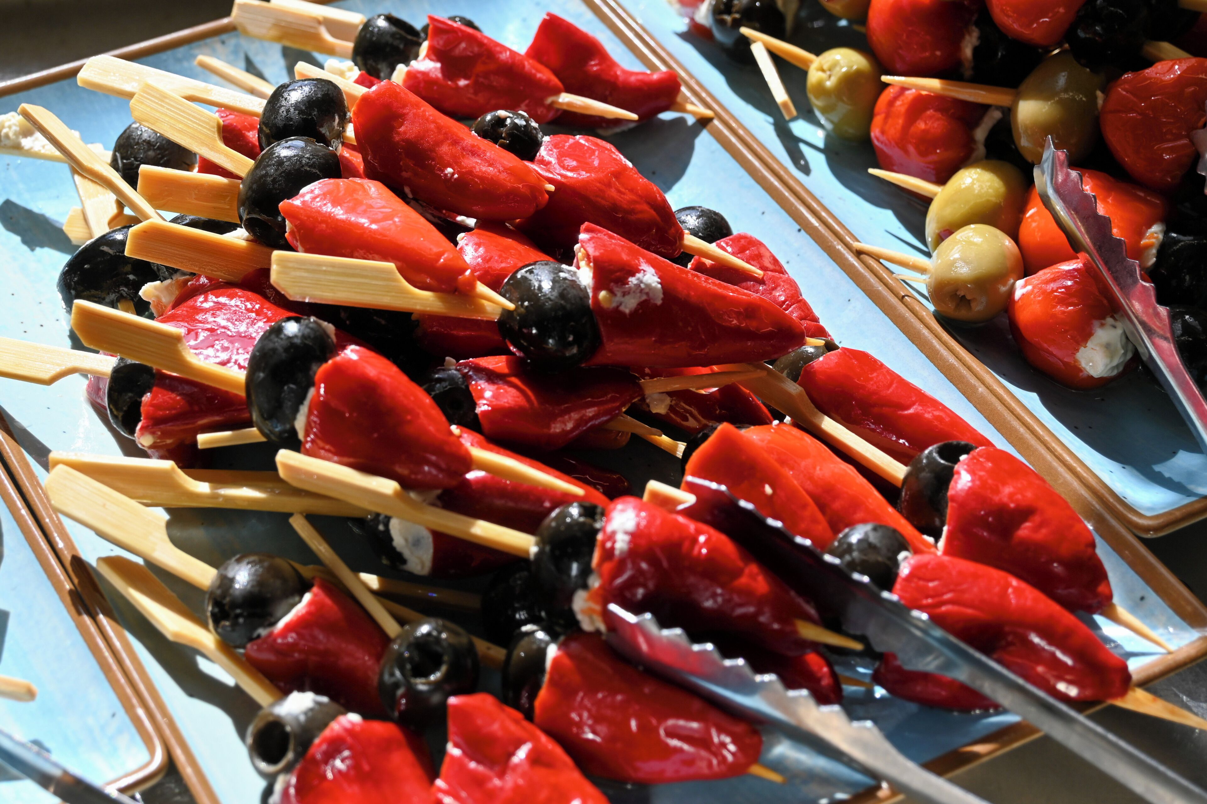 A tray of skewers with red peppers, olives, and cheese.