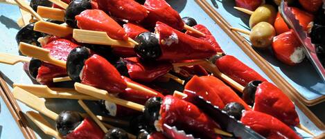A tray of skewers with red peppers, olives, and cheese.