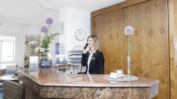 A reception area with a marble counter, a receptionist, and a wooden wall.
