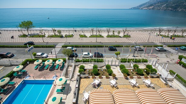 Un hotel con piscina, zona de estar al aire libre y vista al mar.