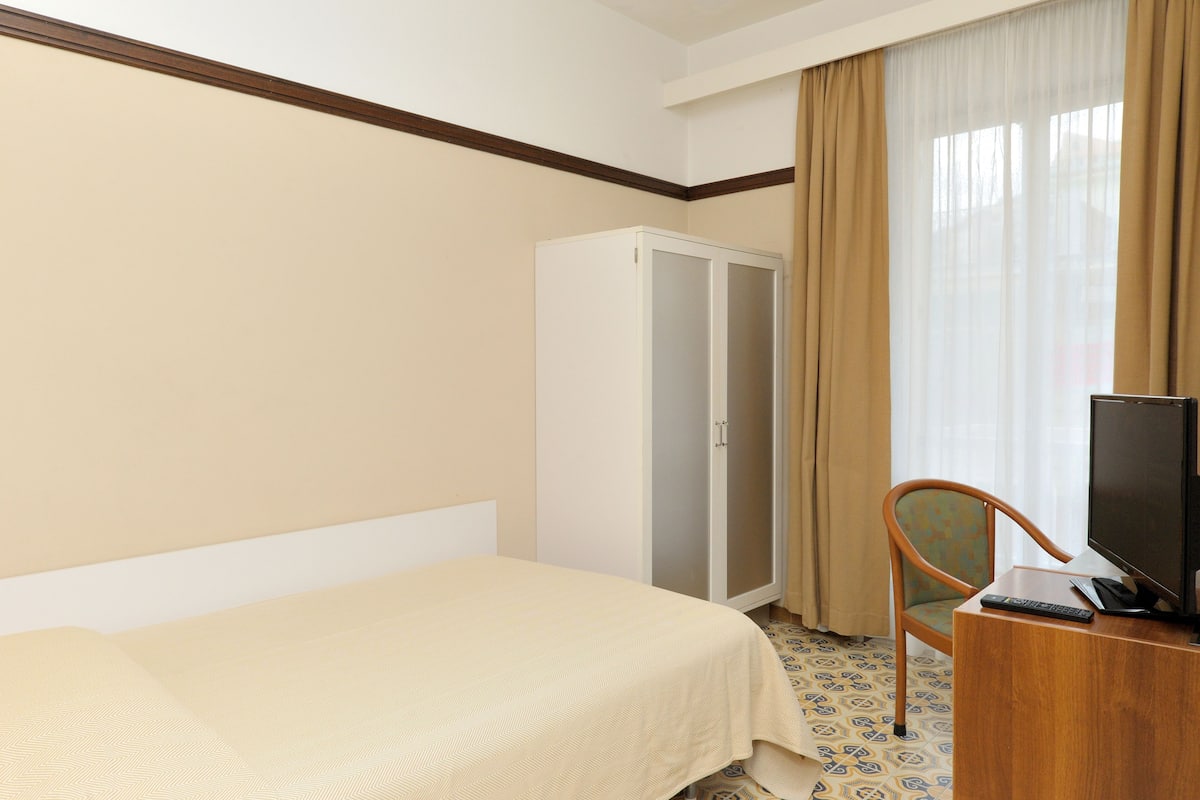 Une chambre d’hôtel comprenant un lit, une armoire, un bureau avec une télévision et une chaise.