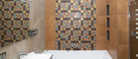 Une salle de bain avec une baignoire blanche, un lavabo avec un miroir et un espace douche.