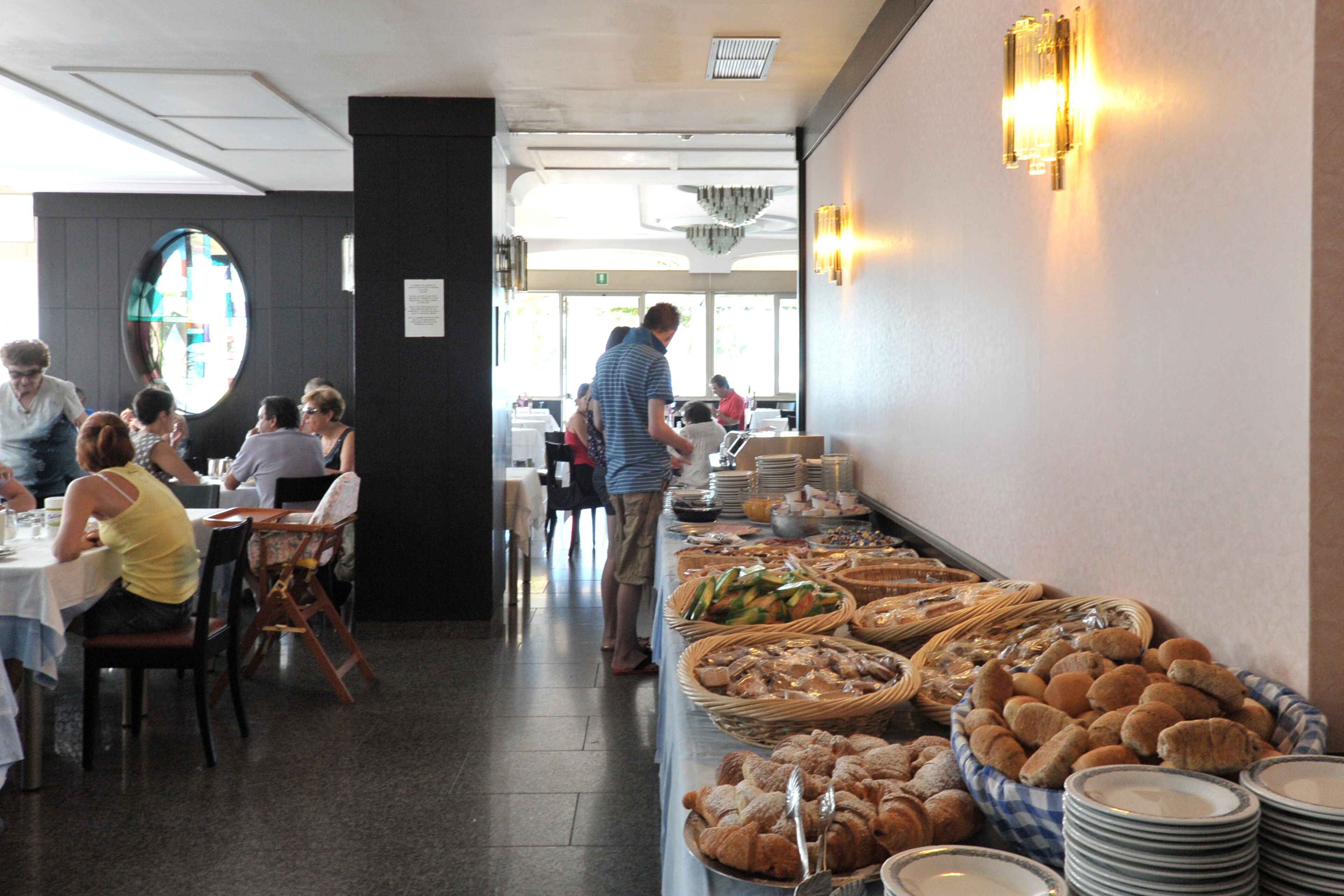 Una mesa de buffet con diferentes alimentos y un grupo de personas comiendo.