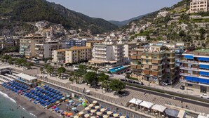 Un pueblo costero con playa, edificios y montañas al fondo.