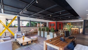 A spacious living area with a wooden coffee table, sofas, and a red accent wall. - Mika Suites (Bogotá)