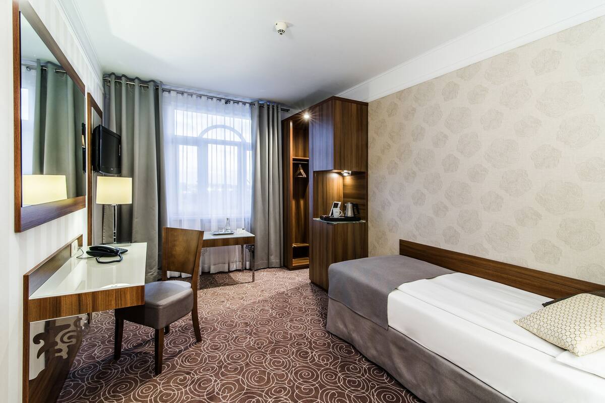 Une chambre d’hôtel comprenant un lit, un bureau avec une chaise, une télévision et une armoire.