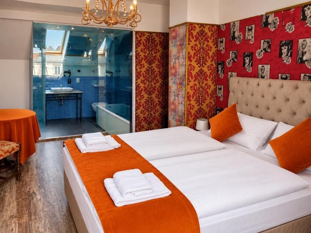 A hotel room with a bed, a bathroom, a small table, and a chair.