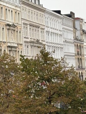 A row of classical buildings with ornate facades and a tree in the foreground. - Hotel Village (Hamburg)