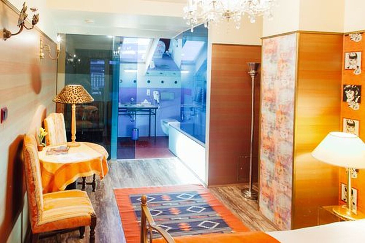 A hotel room with a dining area, a chandelier, and a view of the kitchen.