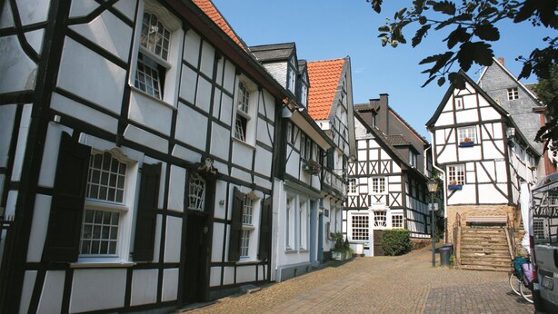 Uma rua estreita de paralelepípedos, ladeada por edifícios tradicionais de enxaimel.