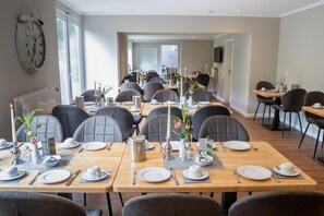 A dining area with multiple tables set for service, chairs, and a clock on the wall. - Hotel Landhaus Knappmann (Essen)