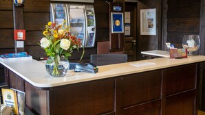 Bancada de recepção com um vaso de flores, um relógio e um quadro de menu.