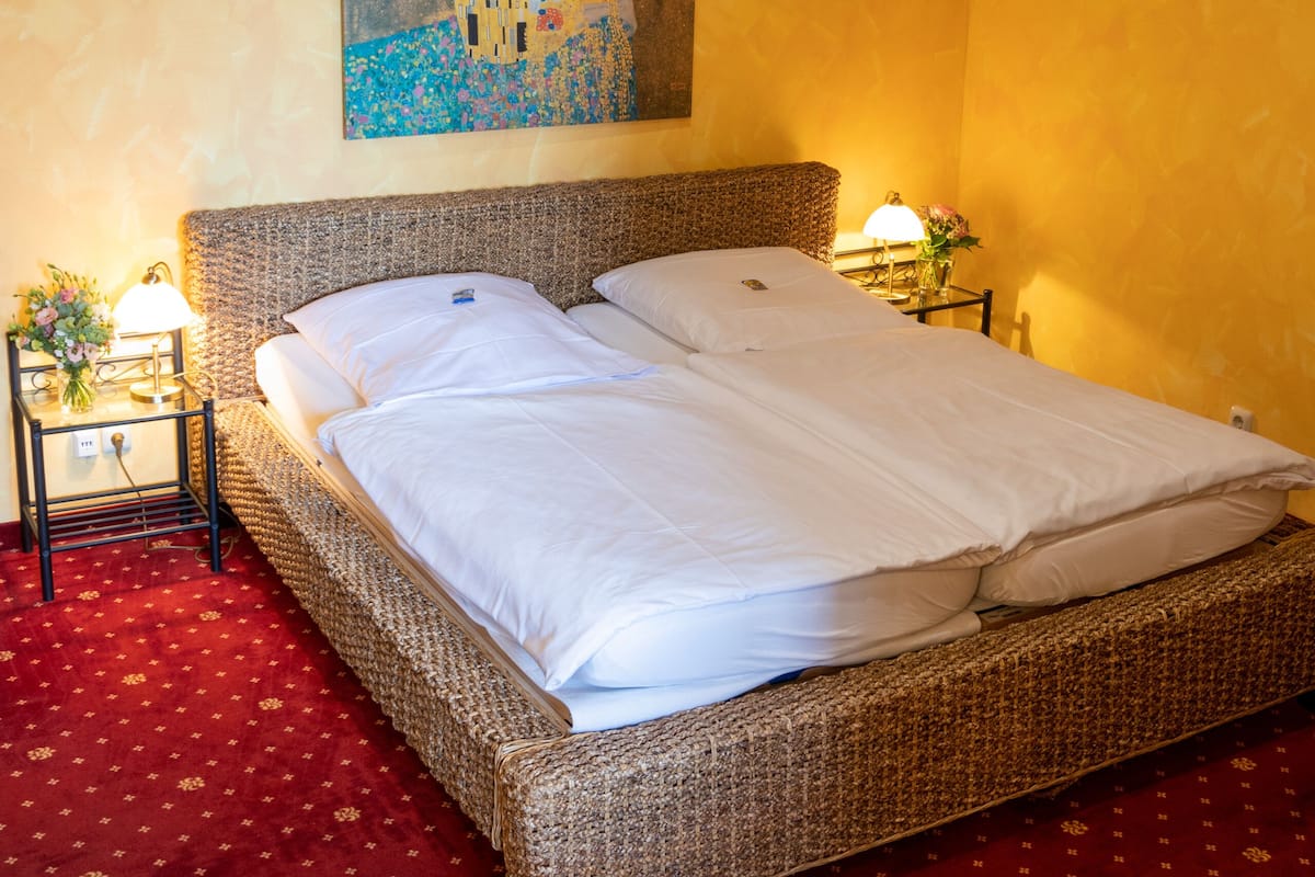 A room with a large bed, a painting on the wall, and a red carpet.