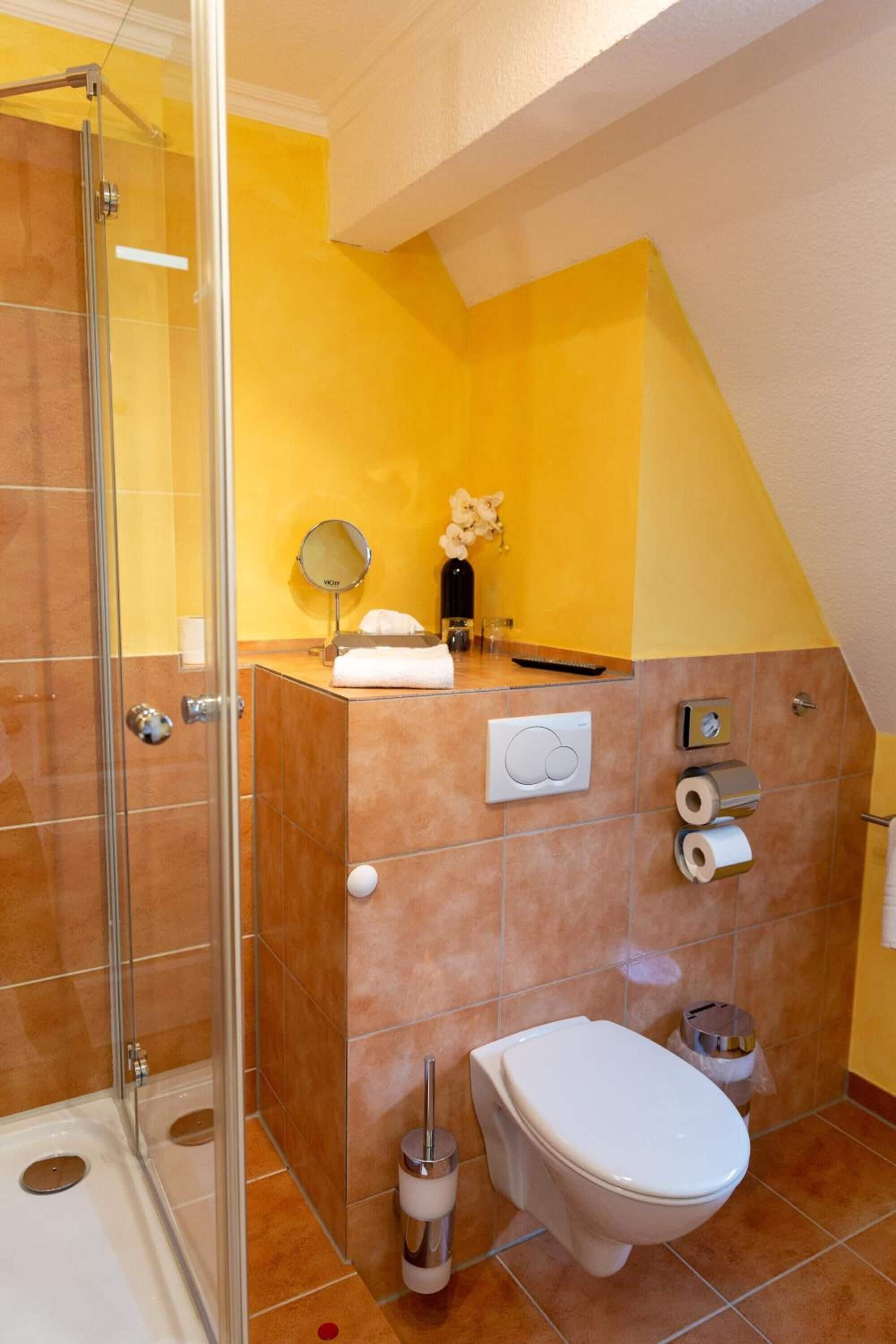 Een badkamer met een glazen douchecabine, toilet en een wastafel met spiegel.