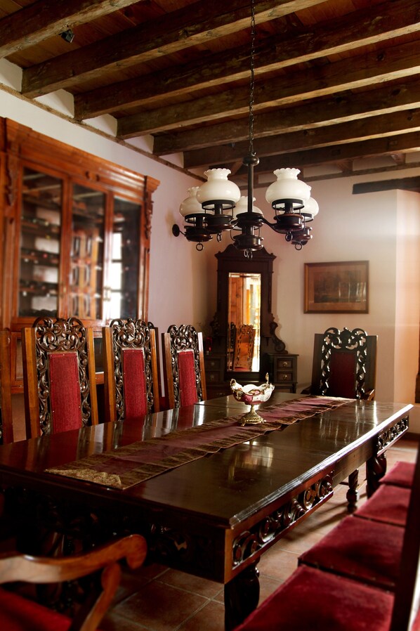 Un comedor con una larga mesa de madera, sillas ornamentadas y un candelabro.