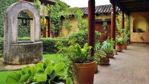 Un patio con una fuente de piedra, plantas en macetas y una pérgola de madera.