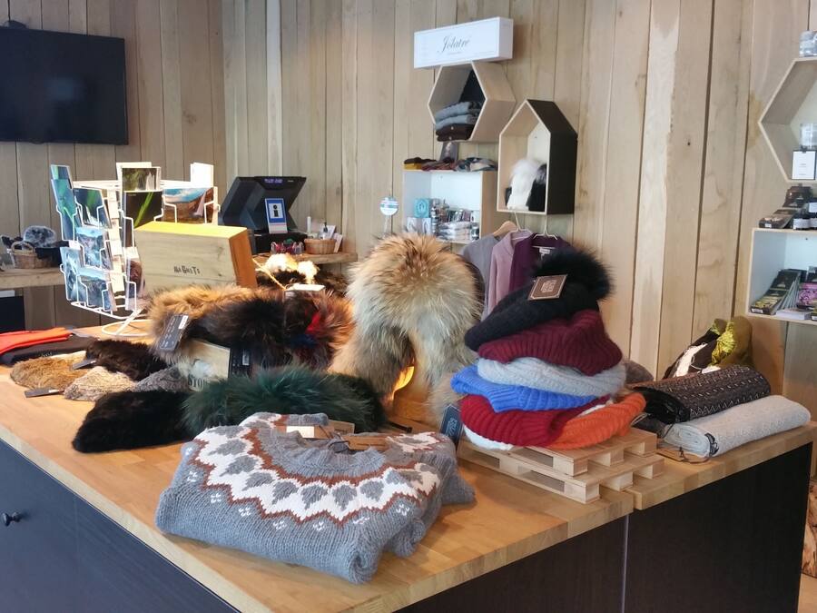 A store with wooden shelves displaying various items like hats, scarves, and bags.