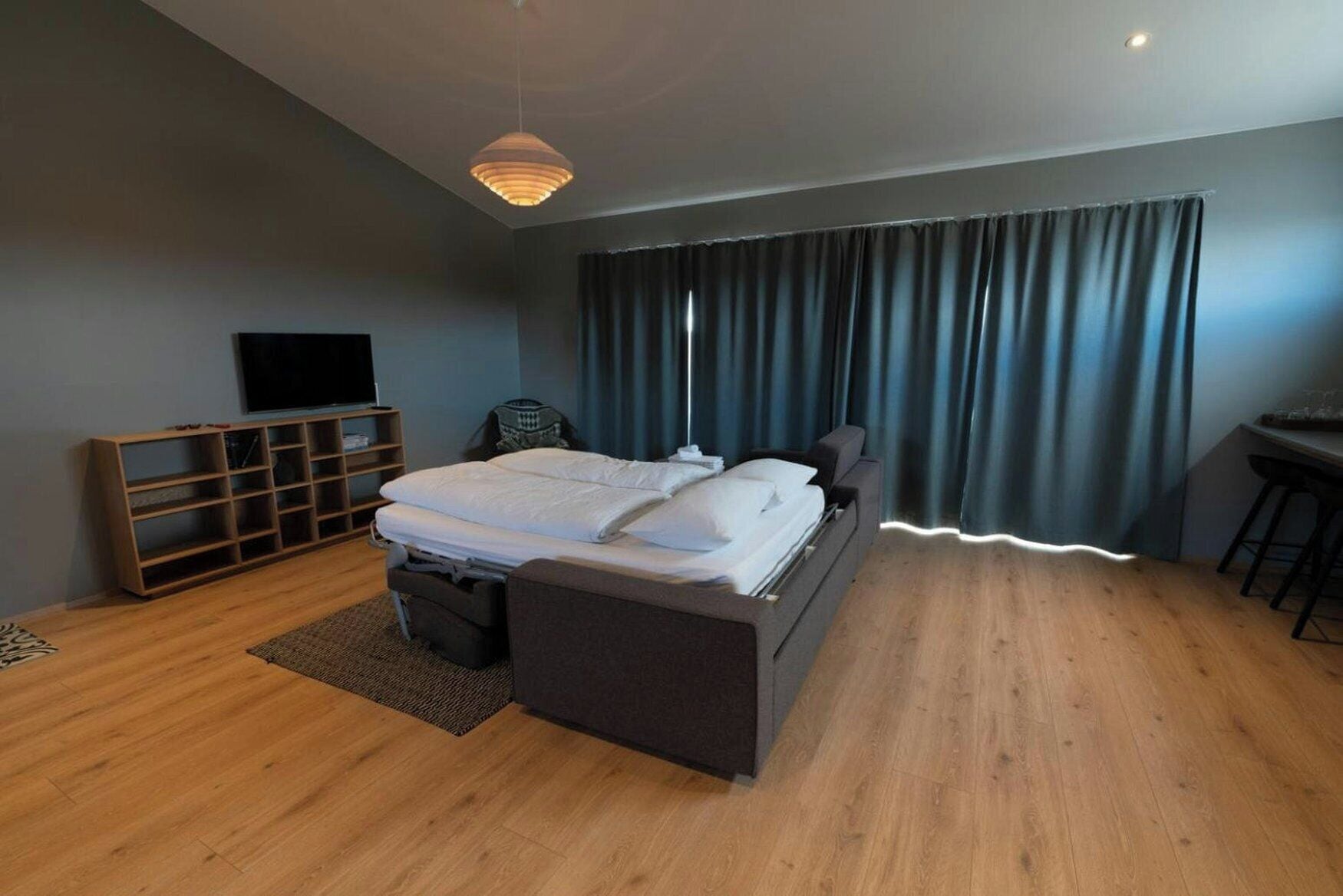 A modern bedroom with a bed, a TV, a desk, and a chair.