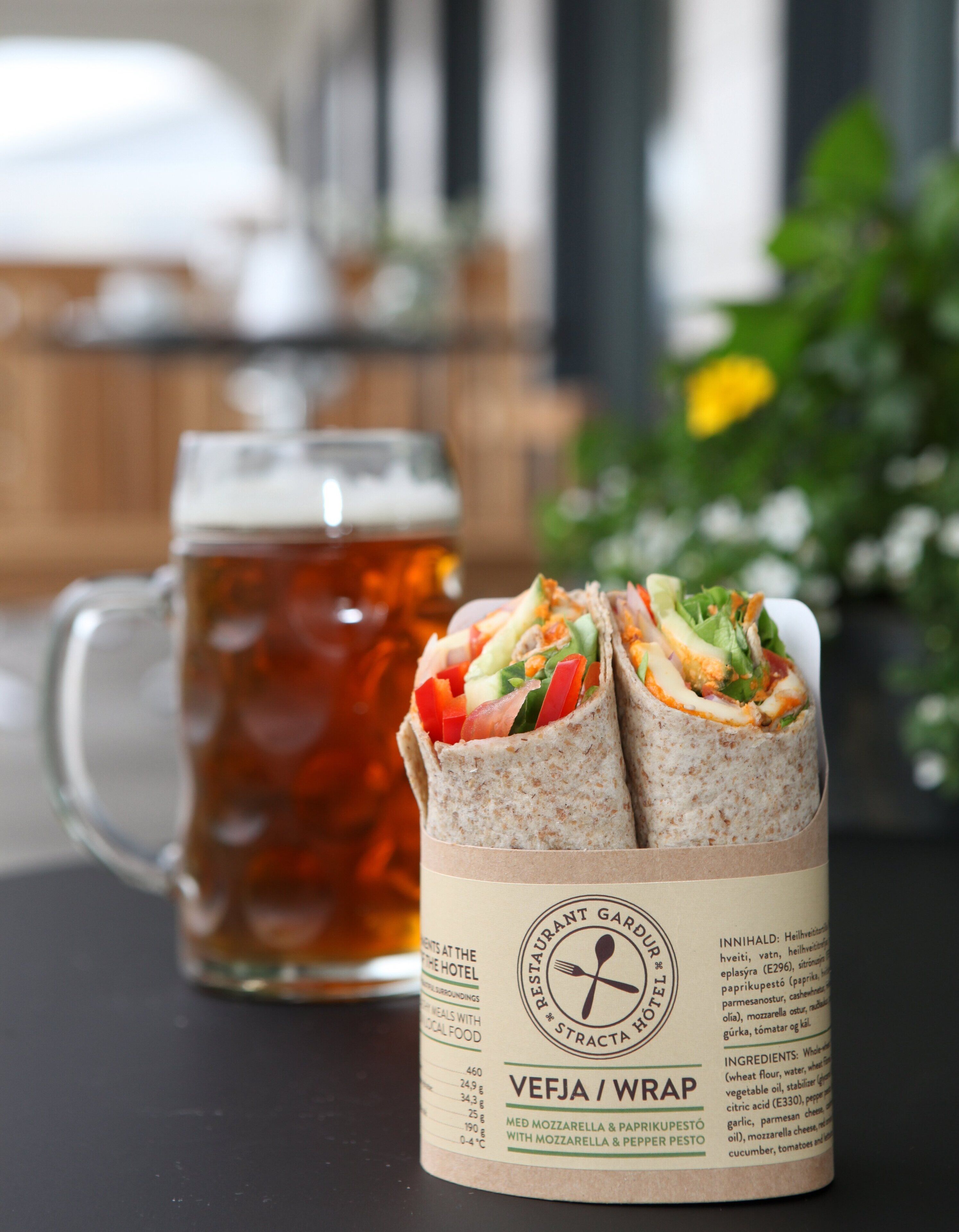 A meal of wraps and a mug of beer on a table.