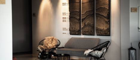 A modern lobby with a grey sofa, black chairs, and a textured wall art piece.