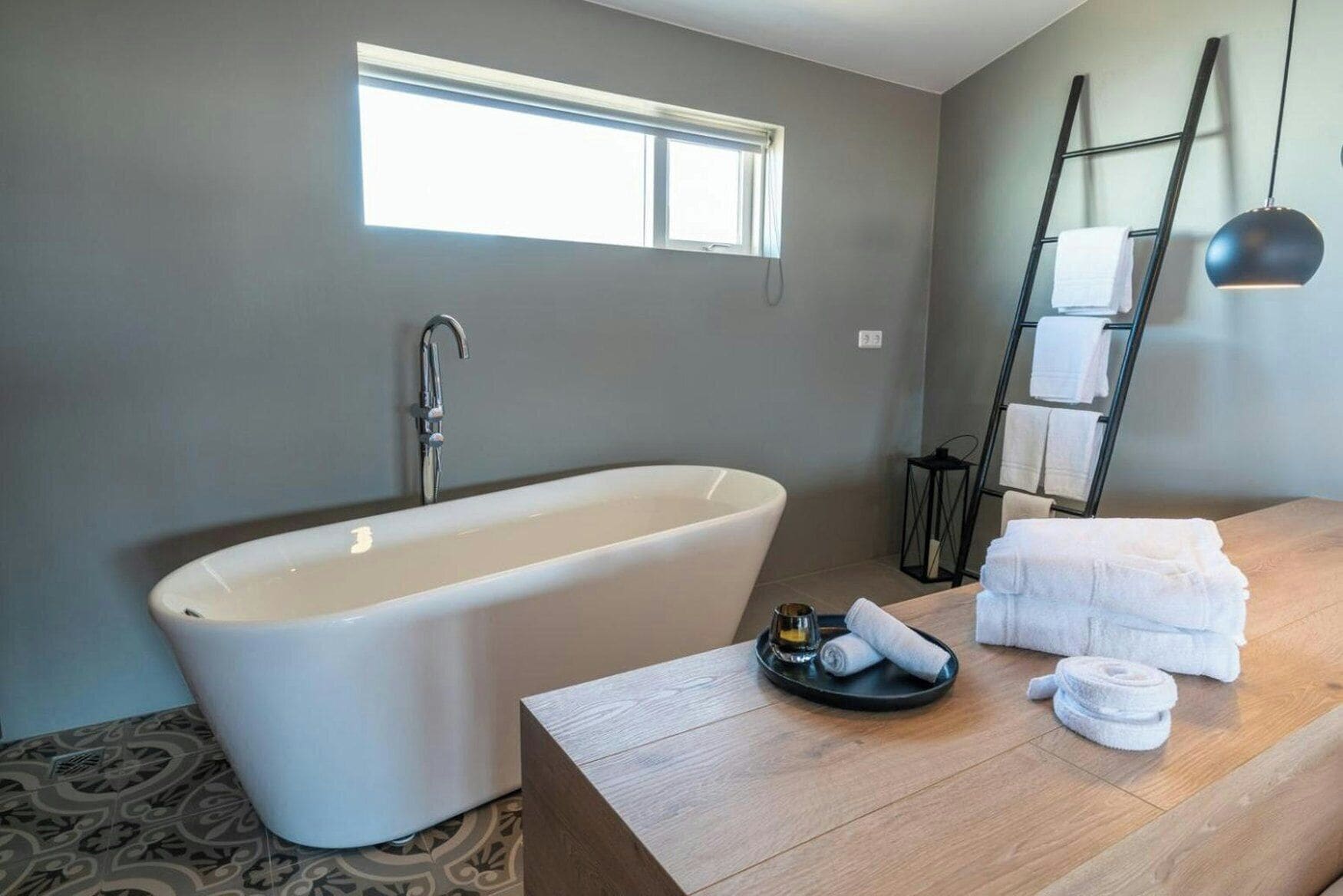 A modern bathroom with a freestanding bathtub, a wooden vanity, and a towel rack.