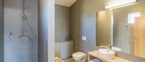 A modern bathroom with a shower, toilet, and sink.