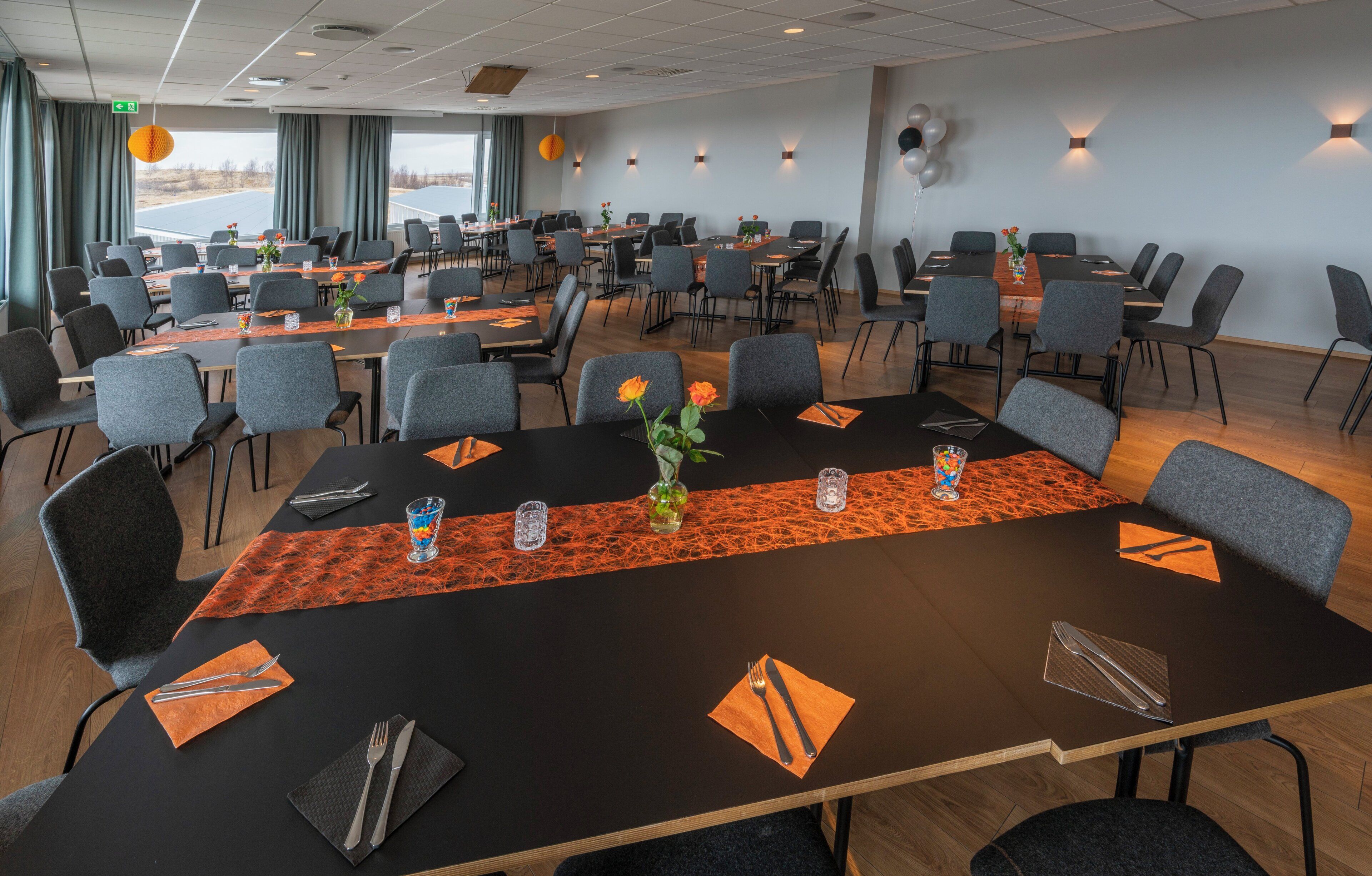Une salle de conférence équipée de plusieurs tables, de chaises et offrant une vue sur l’extérieur.