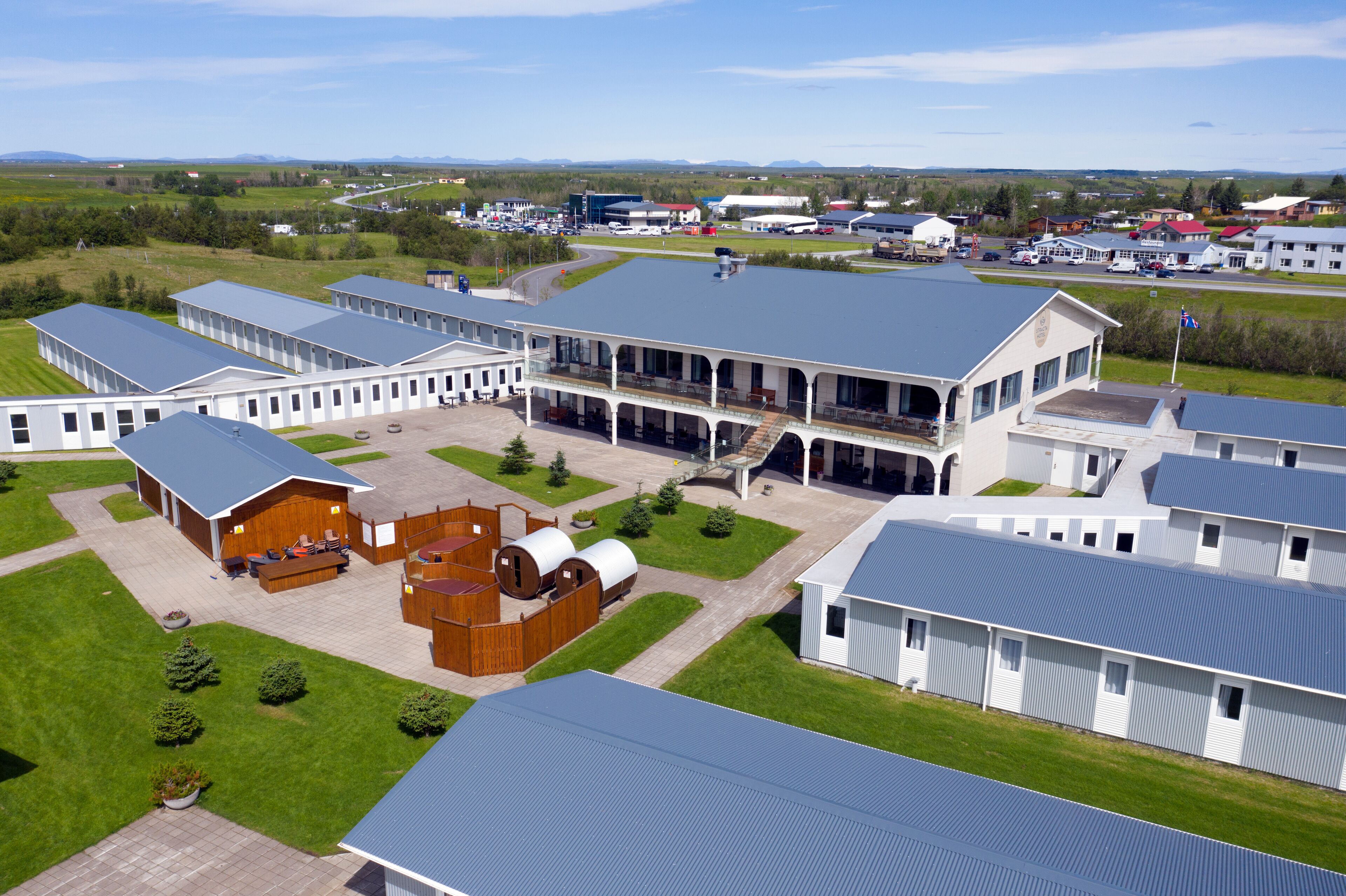 Un vaste complexe industriel comprenant plusieurs bâtiments, notamment une structure centrale dotée d’un balcon et plusieurs bâtiments plus petits avec des toits plats.
