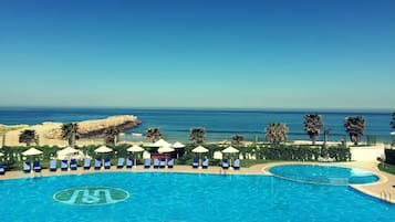 Una piscina techada, una piscina al aire libre, sombrillas