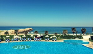 A resort pool with a clear view of the ocean and a sandy beach. - Grand Mogador SEA VIEW (Tangier)
