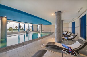Una piscina techada, una piscina al aire libre, sombrillas