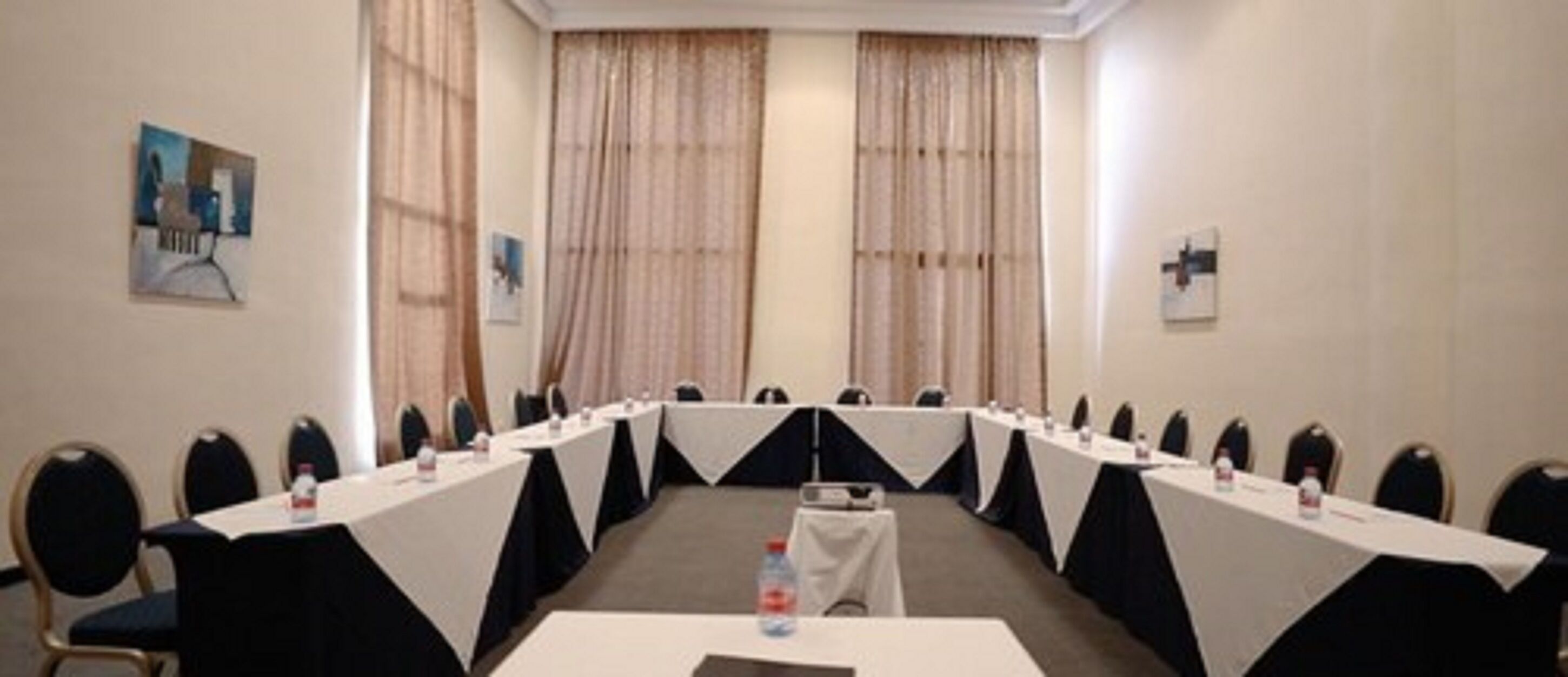 Un salón de conferencias con una larga mesa, sillas y una pantalla para proyector.