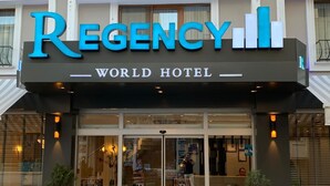 The exterior of the Regency World Hotel with a prominent entrance, large glass doors, and potted plants at the entrance. - Regency World Suite Istanbul (Istanbul)