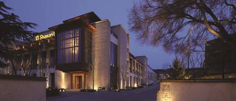 A modern hotel with a prominent sign, a well-lit entrance, and a clear pathway leading to the building.